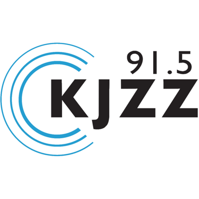Logo for KJZZ 91.5 radio station: black font against a white background, with a series of concentric semi-circles on the left side, in blue.