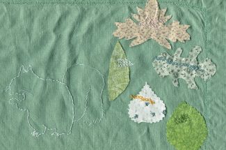 Green linen embroidered with the white outline of a squirrel, and five leaf shapes cut from multiple colors of fabric secured to the linen with cross stitches in various colors.