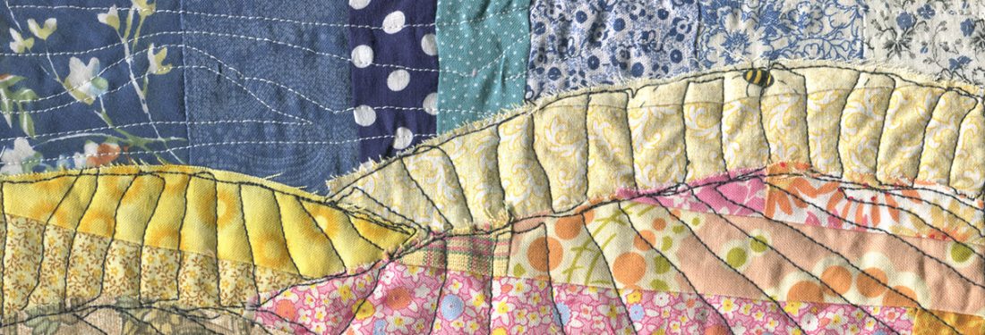 Illustrationdone in fabric, quilted landscape with small person looking over vast hills covered in crops.